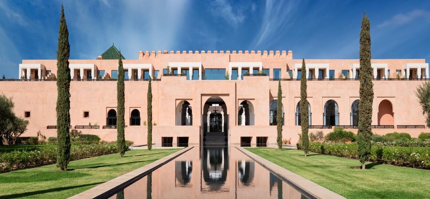 Elegant pink palace with reflective water pool and clear blue sky.