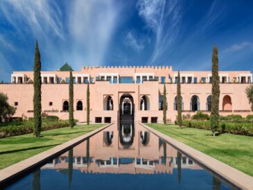 Elegant pink palace with reflective water pool and clear blue sky.