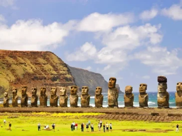Moai statues standing on Easter Island with tourists nearby.