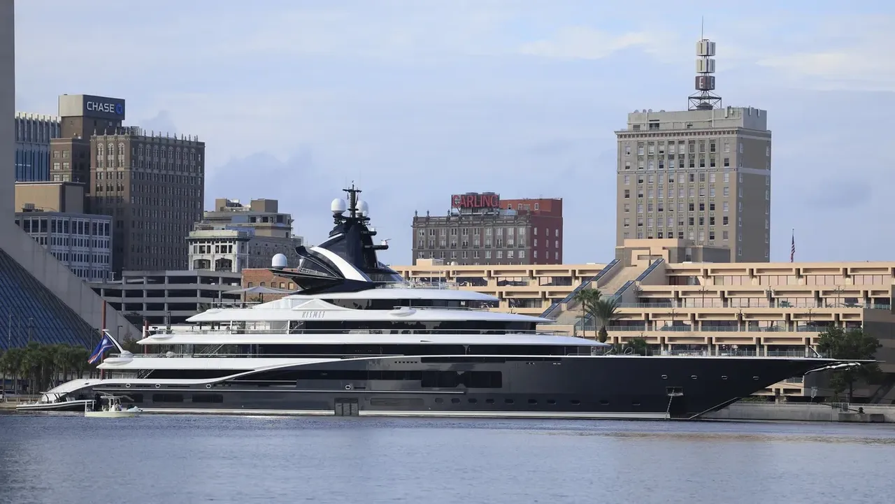 A luxurious yacht docked near a city waterfront with buildings in the background.