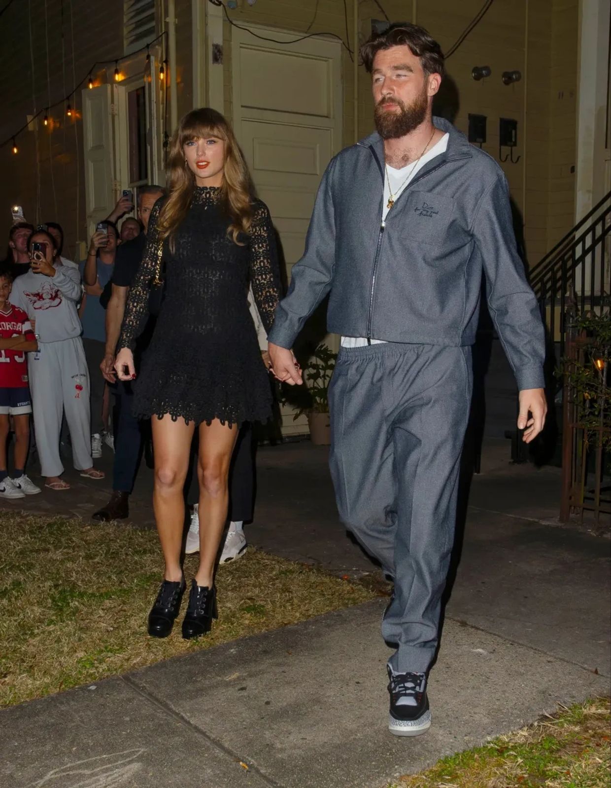 A couple walking hand in hand, dressed in contrasting outfits.