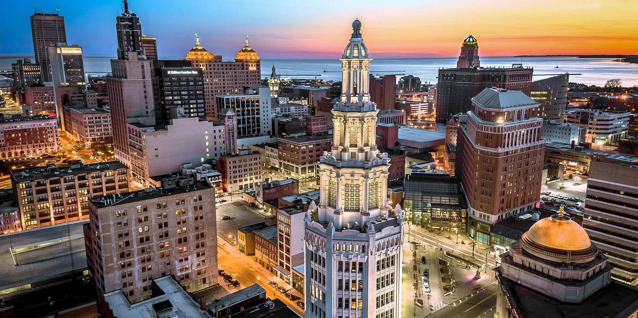 City skyline at sunset with illuminated historic tower.