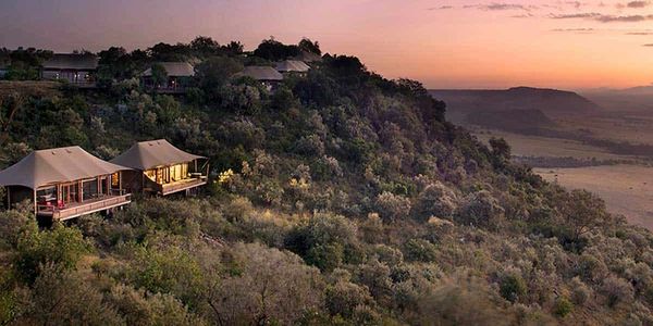Sunset view of a hillside lodge surrounded by lush greenery.