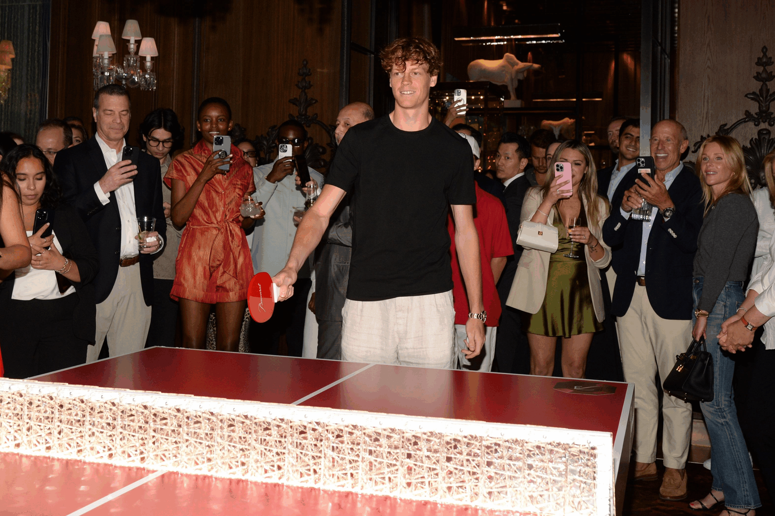 Person playing ping pong at crowded event.